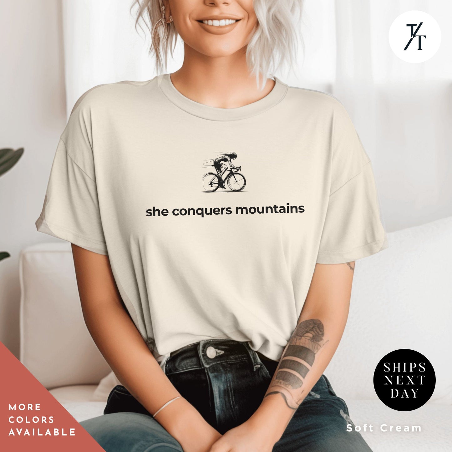 a woman sitting on a couch wearing a shirt that says she conquers mountains