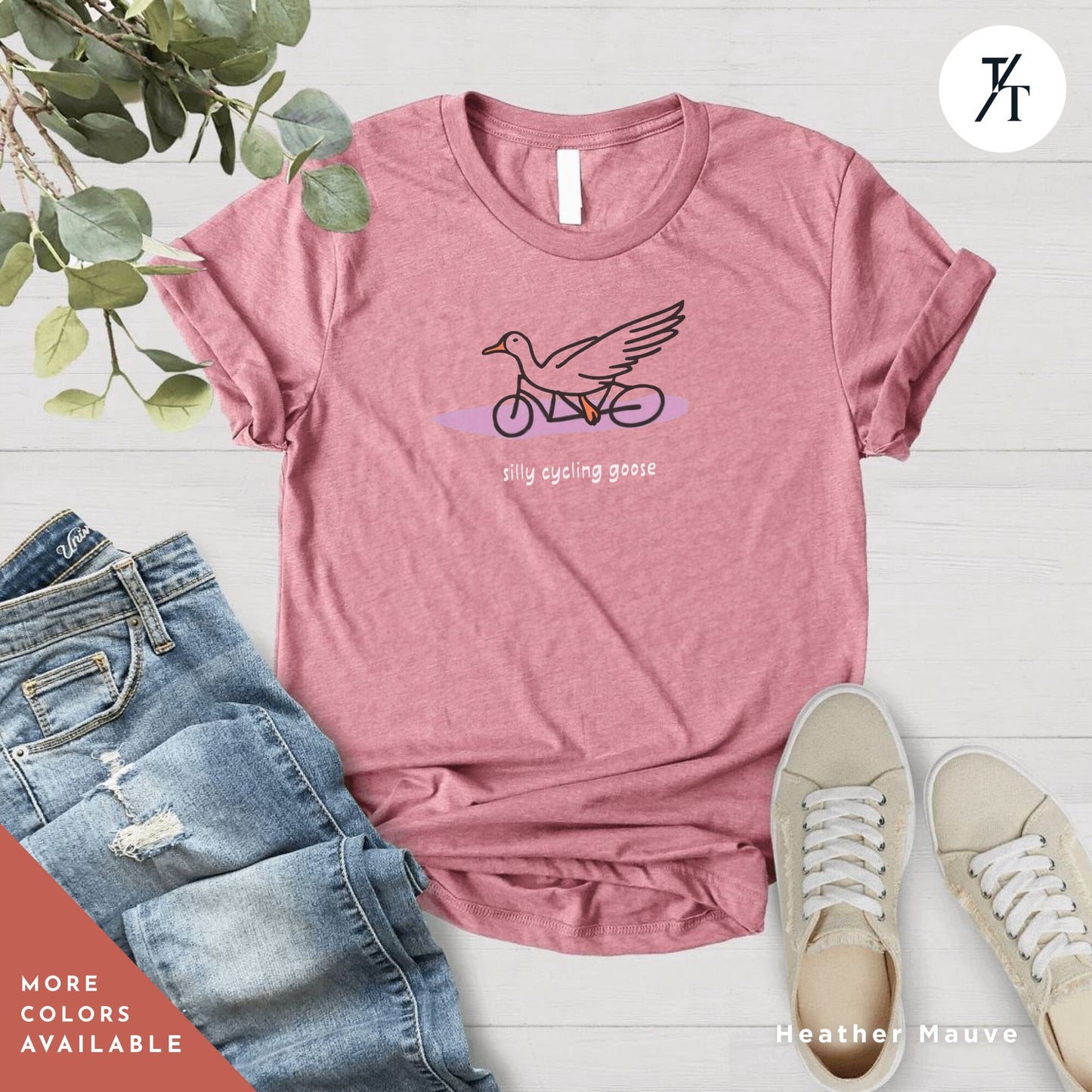 a pink shirt with a bird on it and a pair of jeans next to it