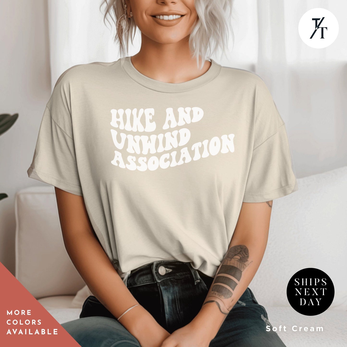 a woman sitting on a couch wearing a shirt that says hike and unwind association