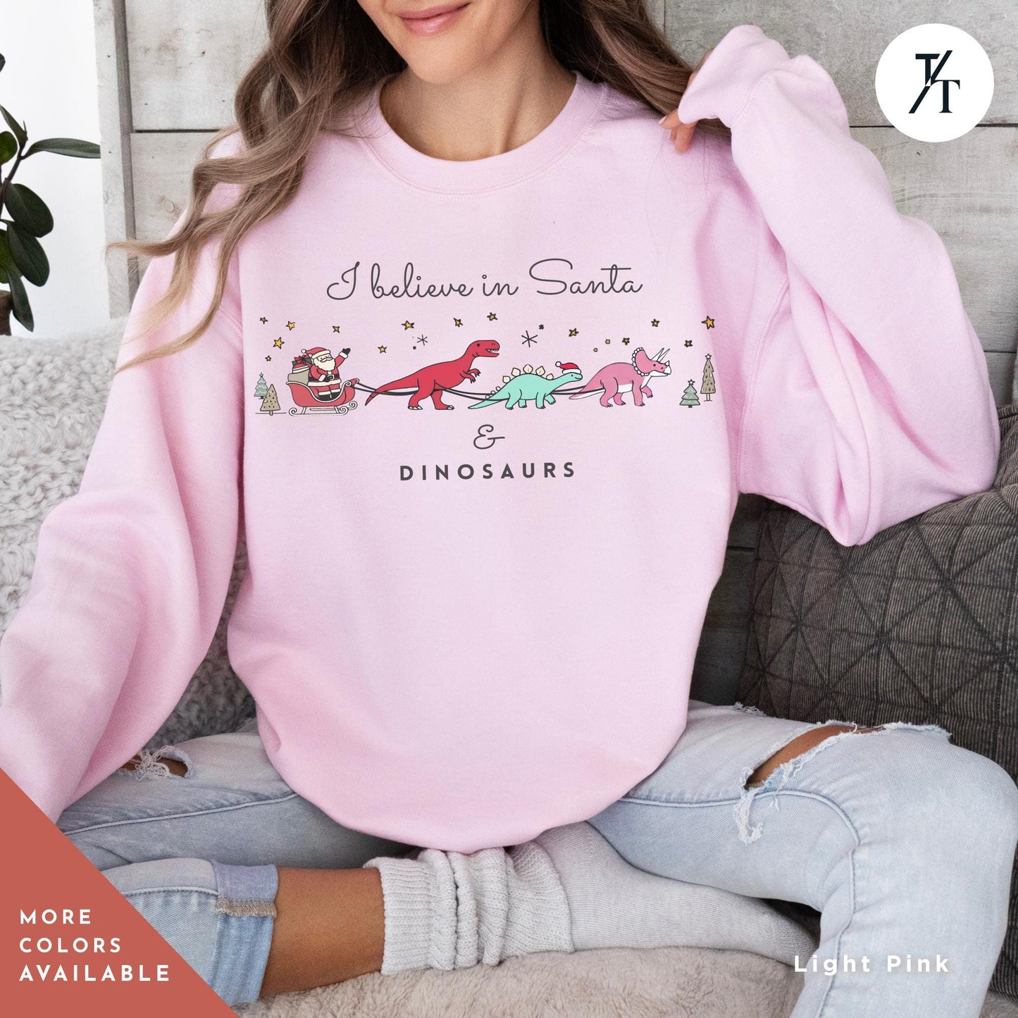 a woman sitting on a couch wearing a pink sweatshirt, I believe in santa and dinosaurs sweatshirt, Christmas Sweatshirt, I Believe In Santa Dinosaurs Sweatshirts, Christmas Gifts Holiday Sweater