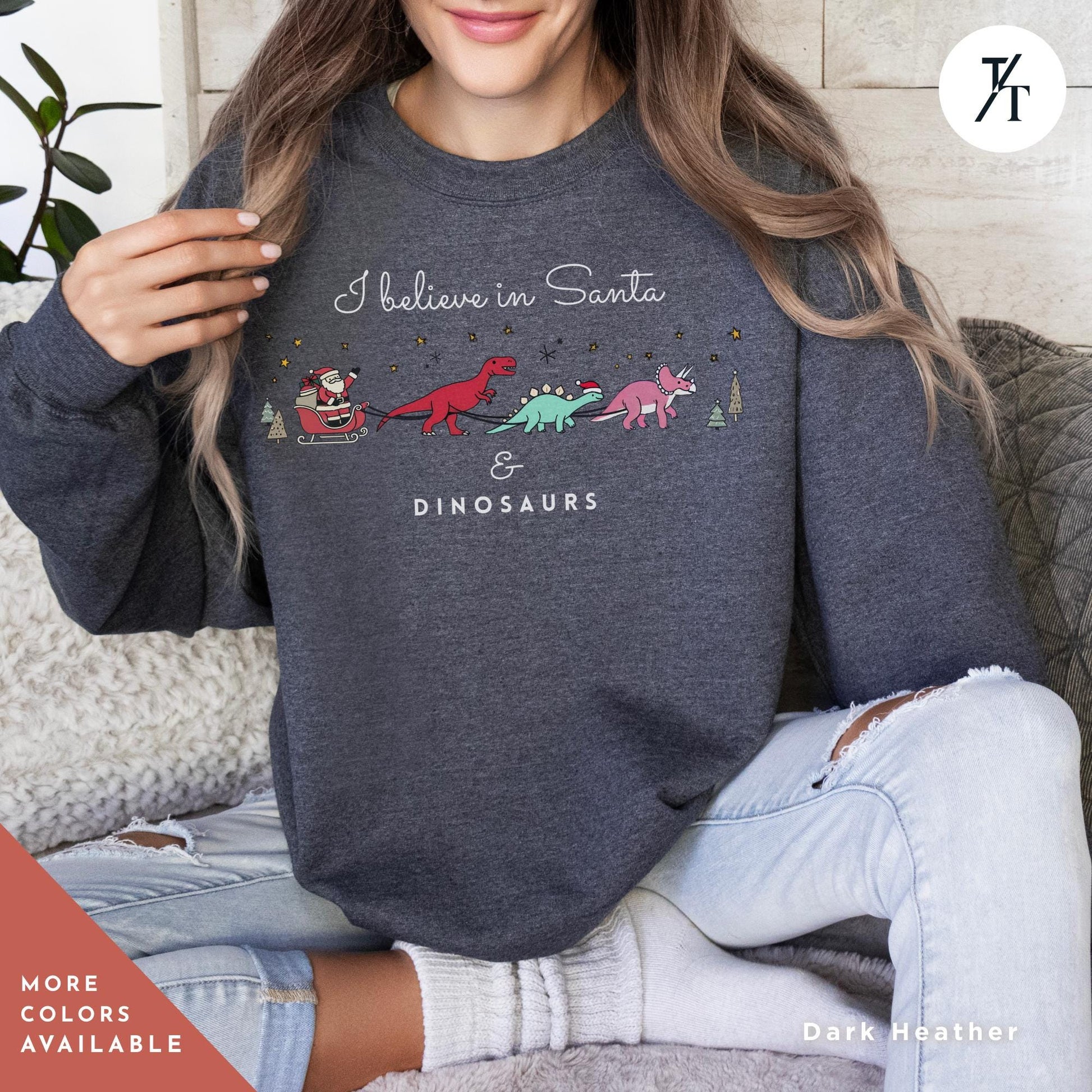 a woman sitting on a couch wearing a sweatshirt with dinosaurs on it, I believe in santa and dinosaurs sweatshirt, Christmas Sweatshirt, I Believe In Santa Dinosaurs Sweatshirts, Christmas Gifts Holiday Sweater