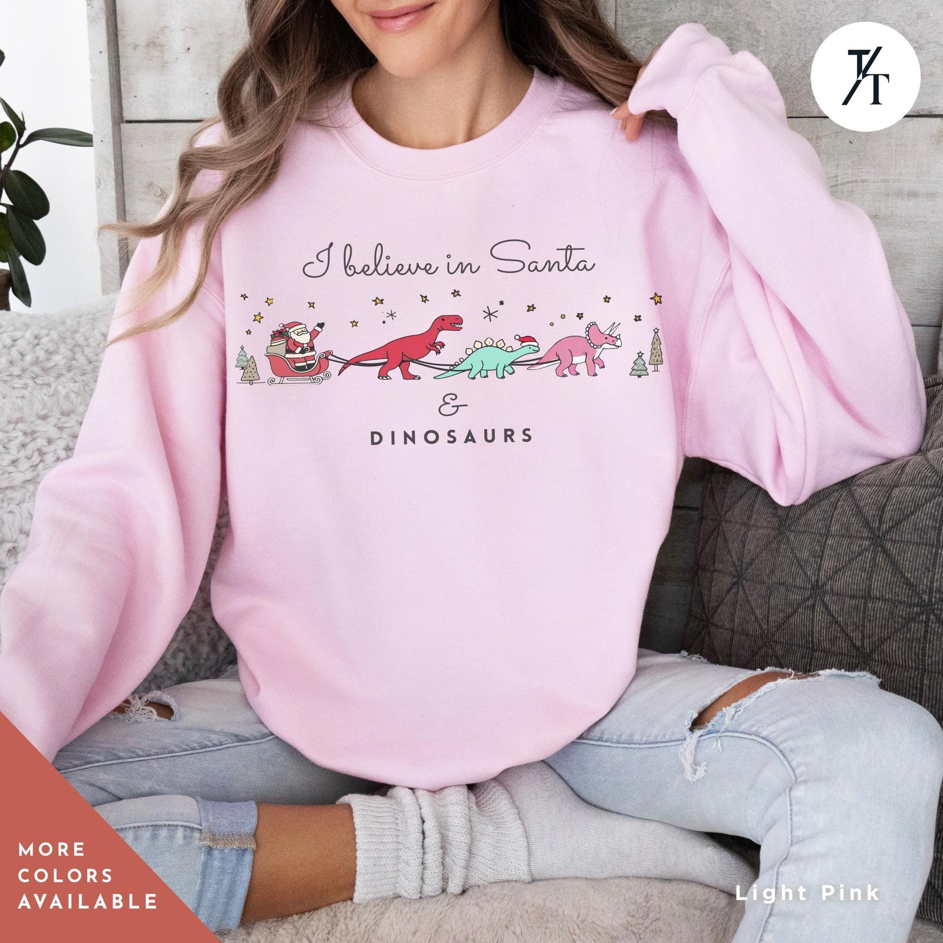 a woman sitting on a couch wearing a pink sweatshirt, I believe in santa and dinosaurs sweatshirt, Christmas Sweatshirt, I Believe In Santa Dinosaurs Sweatshirts, Christmas Gifts Holiday Sweater