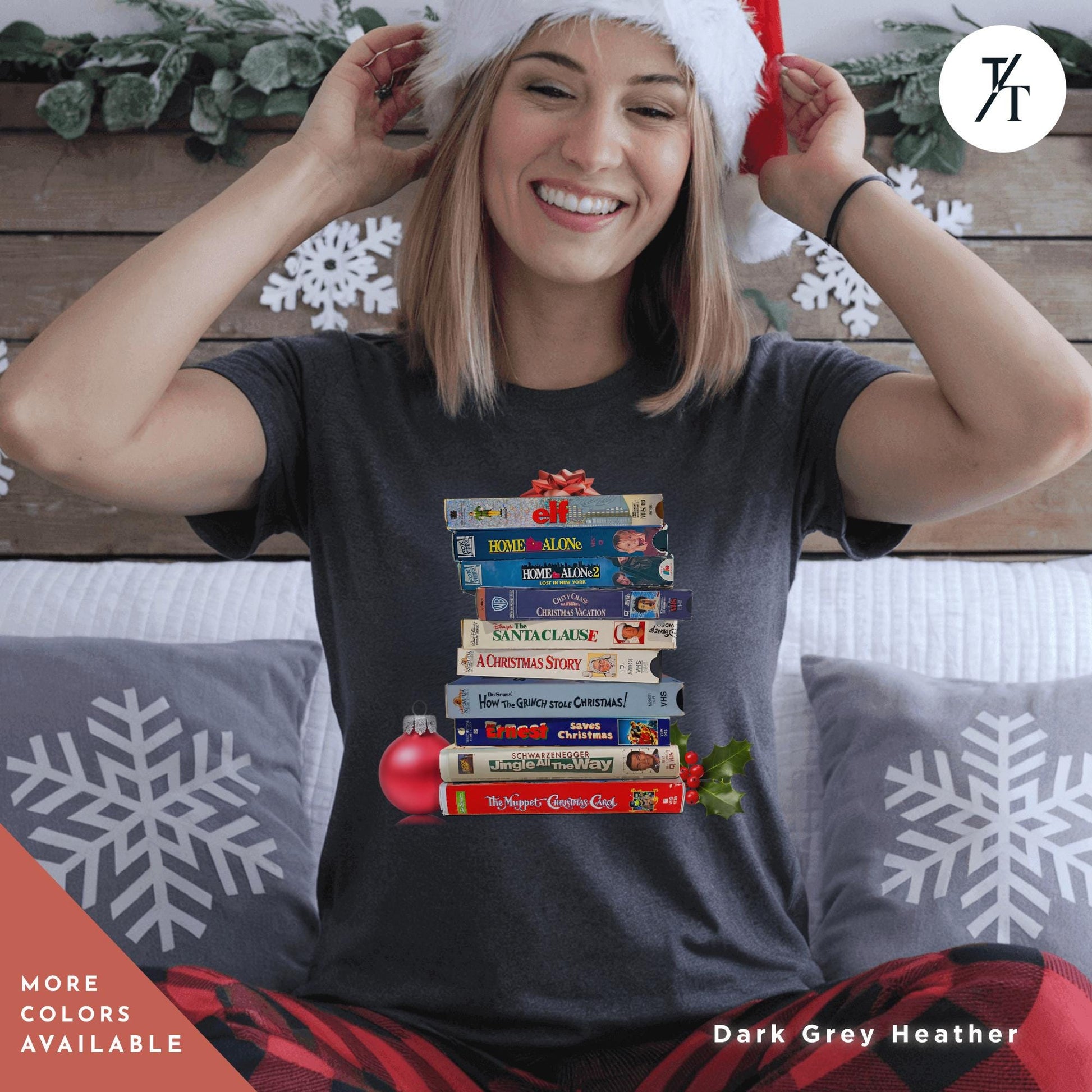 a woman sitting on a bed wearing a grey shirt  with stack of vhs tapes on top of each other,  Vintage Christmas Movies Vhs Shirt Christmas Crewneck, Retro VHS Xmas Tapes Gift For Her, Family Reunion Shirt, 1990s Holiday Sweatshirt