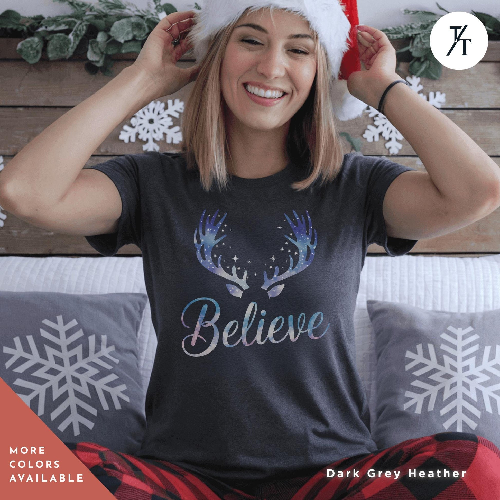 a woman sitting on a bed wearing a christmas hat Believe in Miracles Santa Shirt, Christmas Miracle Reindeer Shirt, Merry Christmas Tee, Believer Tee, Santa Believe Shirts Believe Quote